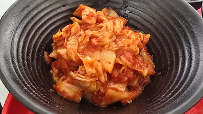 OMMA Chicken Soup served in a black bowl, featuring tender shredded chicken in a rich broth with red pepper flakes and aromatics. — Items: Chicken Soup