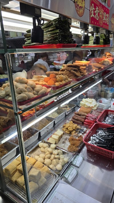 Display case of Chinese restaurant food items including fried chicken, buns, vegetables, fish balls, tofu and various prepared dishes at JustEat Nasi Lemak Economic Bee Hoon. — Items: Fried Chicken · Buns · Carrots · Potatoes · Fish Balls · Tofu · Fried Items · Pastries · Braised Items