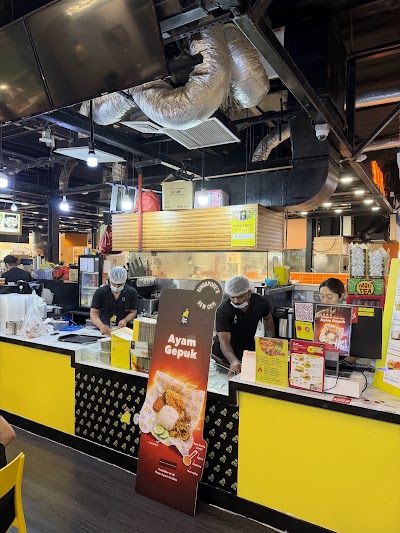 Papa Ayam food stall displaying Ayam Gepuk (fried chicken) with menu signage in a food court setting with yellow branding and kitchen staff. — Items: Ayam Gepuk