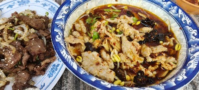 San Gu Cuisine dishes featuring beef with onions and spicy squid with black fungus and corn served on blue and white porcelain plates. — Items: Beef with Onions · Spicy Squid with Black Fungus and Corn