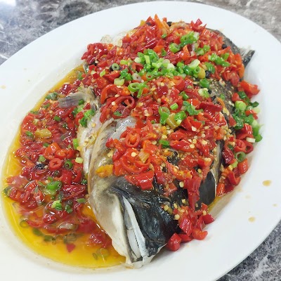 Steamed whole fish topped with diced red chili peppers, green onions, and golden oil served on a white plate at San Gu Cuisine restaurant. — Items: Steamed Fish with Spicy Chili and Green Onion