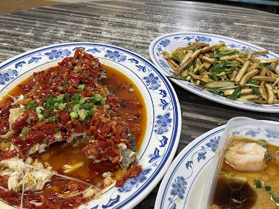 San Gu Cuisine dishes including spicy Chongqing chicken topped with scallions, dry fried beef tendons with green onions, and fish soup with tofu on blue and white porcelain plates. — Items: Chongqing Chicken (La Zi Ji) · Dry Fried Beef Tendons with Green Onions · Fish Soup with Tofu