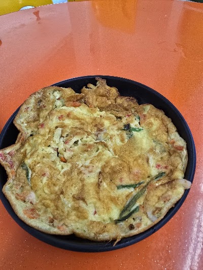 Vegetable omelette with ham, green onions, and spices served on a black plate at Mid's Bakery. — Items: Vegetable Omelette