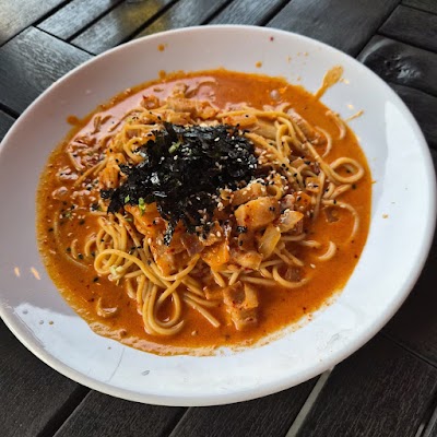 Chickyfish spicy ramen bowl featuring yellow noodles in orange broth, topped with shredded nori seaweed, sesame seeds, and diced chicken. — Items: Spicy Ramen with Chicken