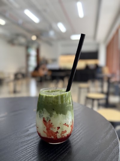 A colorful layered drink with green matcha or herbal layer, white cream or milk layer, and red fruit puree or syrup base, served with a black straw at Meadowbrewsg cafe. — Items: Layered Beverage (Green, White, and Red)