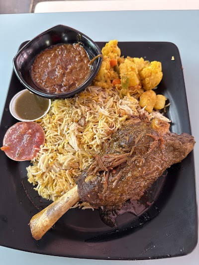 Persian Tandoor grilled lamb chop with saffron rice, fried chickpeas, meat sauce, and salami at a Middle Eastern restaurant — Items: Grilled Lamb Chop · Saffron Rice · Fried Chickpeas · Meat Sauce/Stew · Salami Slice · Yogurt Sauce