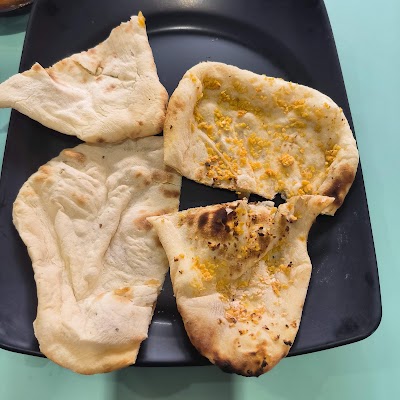 Persian Tandoor naan breads including plain naan and garlic naan served on a black plate — Items: Naan · Garlic Naan