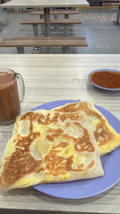 Srisun Prata restaurant meal featuring folded prata bread on blue plate with curry dipping sauce and hot beverage, served in dining area with wooden tables. — Items: Prata · Curry (appears to be dipping sauce) · Beverage (appears to be tea or coffee)