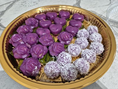 Gold tray of Nonya kueh featuring purple glutinous rice balls and coconut-dusted balls from Kueharmony's Mummiesrella pre-order collection. — Items: Purple Glutinous Rice Balls (Kuih Pulut Hitam) · Coconut-Dusted Balls (Kuih Lopis or similar Nonya kueh)