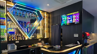 Bar counter at Jewel Music Box Bedok displaying 5 Hours 2 Free Flow for $18 and drink specials from $2-$8 on digital menu board with neon-lit bottle display. — Items: 5 Hours 2 Free Flow $18 · Drink Special $2 · Drink Special $8