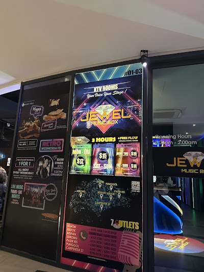 Jewel Music Box KTV karaoke menu board showing pricing: 3 Hours $12, Weekdays $12, Weekends $19, All Day Night $19, Friday-Sunday $19 with free flow beverages included. — Items: 3 Hours Package $12 · Weekends Package $19 · All Day Night Package $19 · Weekdays Package $12 · Friday-Sunday Package $19