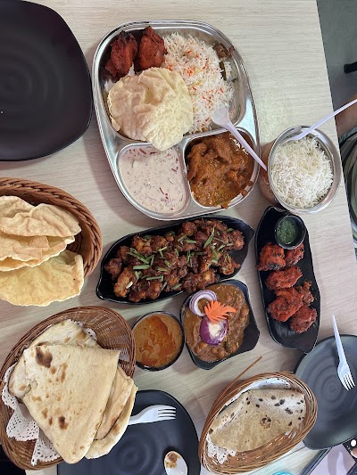 Indian cuisine spread from Khuxi Corner featuring tandoori chicken, naan, roti, paratha, basmati rice, curries, samosas, and traditional chutneys and raita — Items: Tandoori Chicken · Naan · Roti · Paratha · Basmati Rice · Paneer Tikka · Chicken Tikka · Samosa · Dal Curry · Butter Chicken · Raita · Chutneys