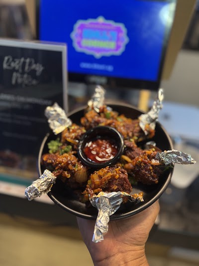 Tandoori Chicken Lollipops served in a black bowl with red dipping sauce at Khuxi Corner Indian Cuisine restaurant. — Items: Tandoori Chicken Lollipops