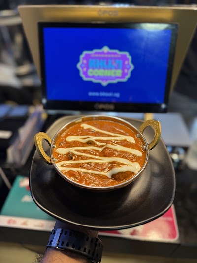 Butter Chicken curry served in a traditional black bowl with golden handles at Khuxi Corner Indian Cuisine restaurant. — Items: Butter Chicken