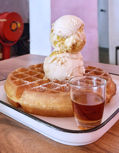 Waffle topped with three scoops of ice cream (vanilla, butter pecan, and strawberry) dusted with powdered sugar, served with iced tea at Lickers restaurant. — Items: Waffle with Ice Cream · Iced Tea
