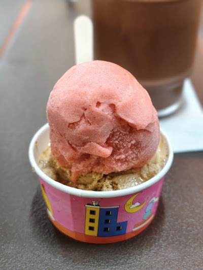 Pink ice cream scoop served in a colorful Lickers branded cup with waffle cone base. — Items: Ice Cream Scoop