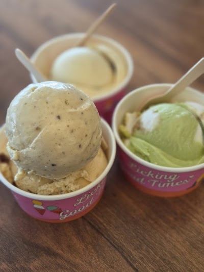Lickers ice cream cups featuring cookies and cream, pistachio, and vanilla ice cream flavors with plastic spoons on wooden surface. — Items: Cookies and Cream Ice Cream · Pistachio Ice Cream · Vanilla Ice Cream