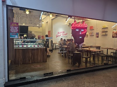 Lickers ice cream parlor storefront with neon signage displaying 'Licking Good Times' ice cream and menu board visible at entrance. — Items: Ice Cream · Licking Good Times · Ice Cream