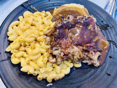 Bradley's Grill plate featuring creamy mac and cheese and grilled meat topped with rich gravy on a blue plate. — Items: Mac and Cheese · Grilled Meat with Gravy