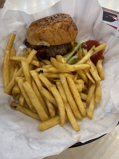Bradley's Grill cheeseburger with sesame seed bun, melted cheese, and beef patty served with golden french fries and ketchup on white paper. — Items: Cheeseburger · French Fries · Ketchup