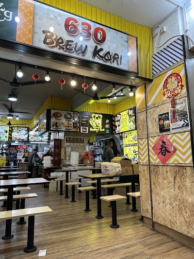 630 Brew Kopi Asian restaurant interior with menu boards displaying noodle and rice dishes, dining tables with benches, and traditional yellow and red decor. — Items: Kopi (Coffee) · Various noodle and rice dishes · Asian cuisine items