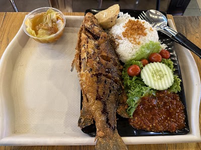 Grilled whole fish served with white rice, sambal, and fresh vegetable sides including cucumber, tomato, and lettuce at Loka Loka Ang Mo Kio restaurant. — Items: Grilled Fish · White Rice · Sambal · Fresh Vegetables · Cucumber · Tomato · Lettuce · Prawn Paste Dip