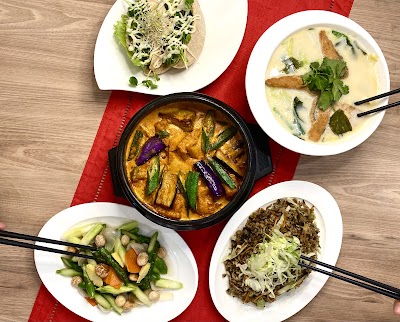 Table spread from Yes Natural Restaurant featuring Thai curry with eggplant, creamy coconut soup with fried tofu, vegetable stir-fry with cashews, brown rice, and spring rolls. — Items: Thai Curry with Eggplant and Green Beans · Creamy Coconut Soup with Fried Tofu · Stir-fried Vegetables with Cashews · Brown Rice with Mixed Vegetables · Spring Rolls or Summer Rolls