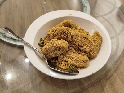 Plate of golden fried chicken pieces served at Yes Natural Restaurant on a white dish with a spoon. — Items: Fried Chicken
