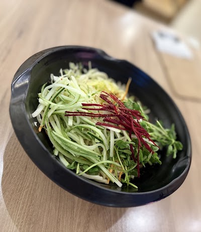 Fresh vegetable salad with mixed green sprouts, shredded daikon, beets, and seasonal greens in a black bowl from Yes Natural Restaurant. — Items: Vegetable Salad with Sprouts and Beets