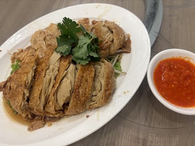 Hainanese Chicken with sliced poached chicken, fresh cilantro garnish, and chili sauce served on white plate at Yes Natural Restaurant. — Items: Hainanese Chicken · Chili Sauce