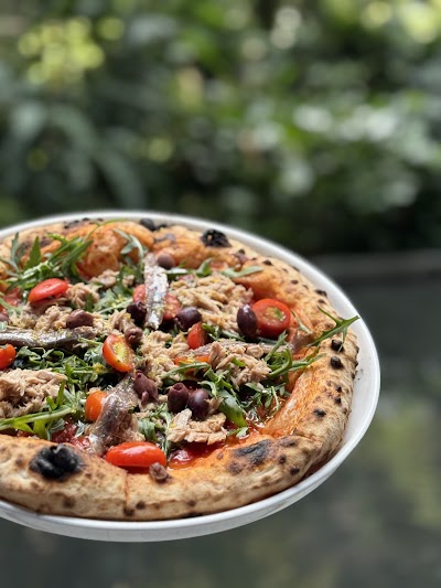 Artisanal pizza topped with shredded tuna, black olives, red peppers, fresh arugula, and herbs from d.o.c Italian Restaurant. — Items: Pizza with Tuna and Black Olives