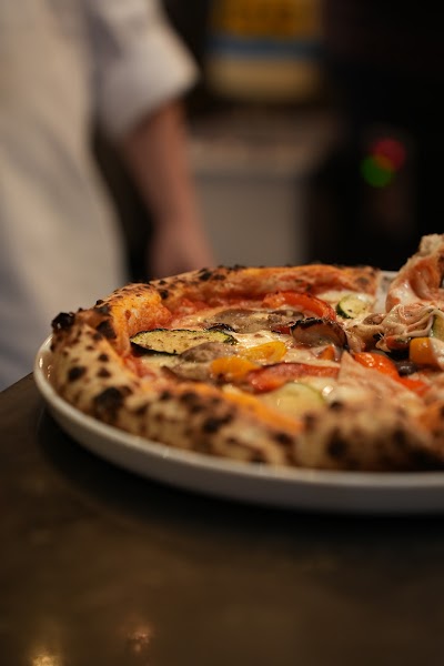 Wood-fired pizza topped with grilled vegetables including zucchini, bell peppers, and mushrooms from d.o.c Italian Restaurant — Items: Vegetable Pizza