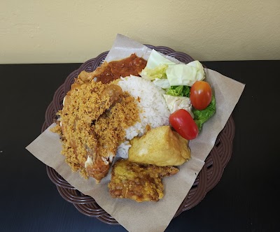 Haryati's fried chicken meal with white rice, crispy potatoes, gravy, and fresh vegetable garnish on brown plate — Items: Fried Chicken · White Rice · Gravy/Sauce · Fried Potato · Fresh Vegetables (Lettuce, Tomato)
