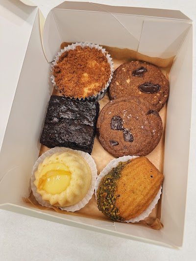 Assorted desserts from The Dessert Party in a box: cinnamon muffin, chocolate brownie, chocolate chip cookie, lemon curd tart, and pistachio cookie. — Items: Cinnamon Crumb Muffin · Dark Chocolate Brownie · Chocolate Chip Cookie · Lemon Curd Tart · Pistachio Cookie
