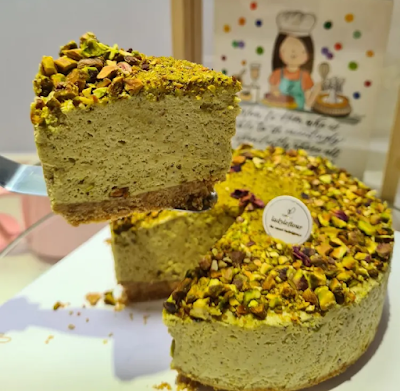LadyLeFlour pistachio cake slices with crushed pistachios topping and green sponge layers displayed on white plate. — Items: Pistachio Cake