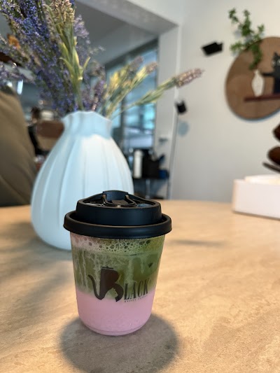 Black Kettle Coffee matcha latte with green matcha on top and pink base layer in a takeaway cup with black lid. — Items: Matcha Latte